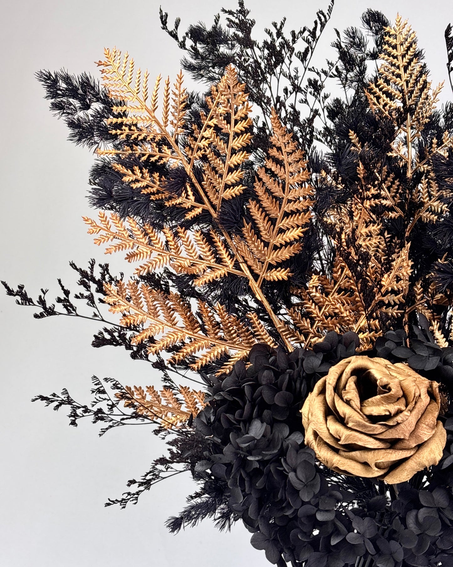Black textured vase with dried flowers on a white and gold pedestal