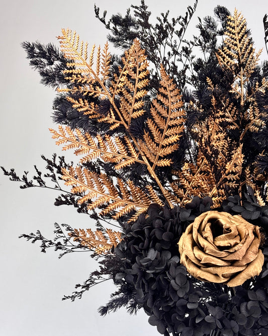 Black textured vase with dried flowers on a white and gold pedestal