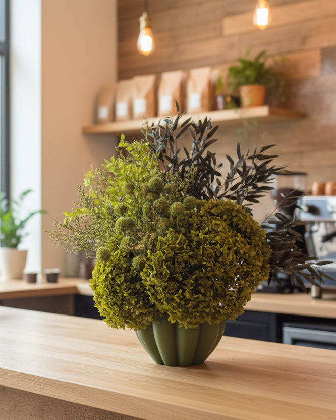 Decorative arrangement of greenery in a pot against a light blue background