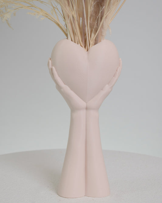 Heart-shaped white vase with dried plants on a light gray background
