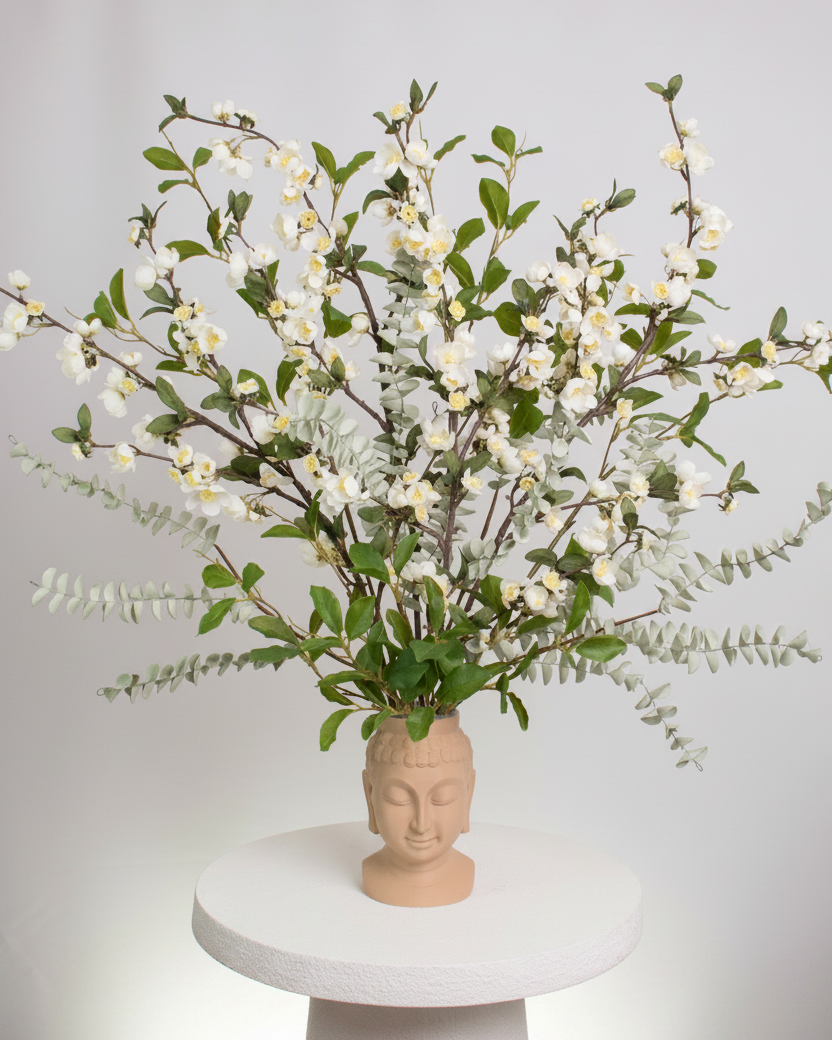 Vase with floral arrangement on a white pedestal against a light gray background