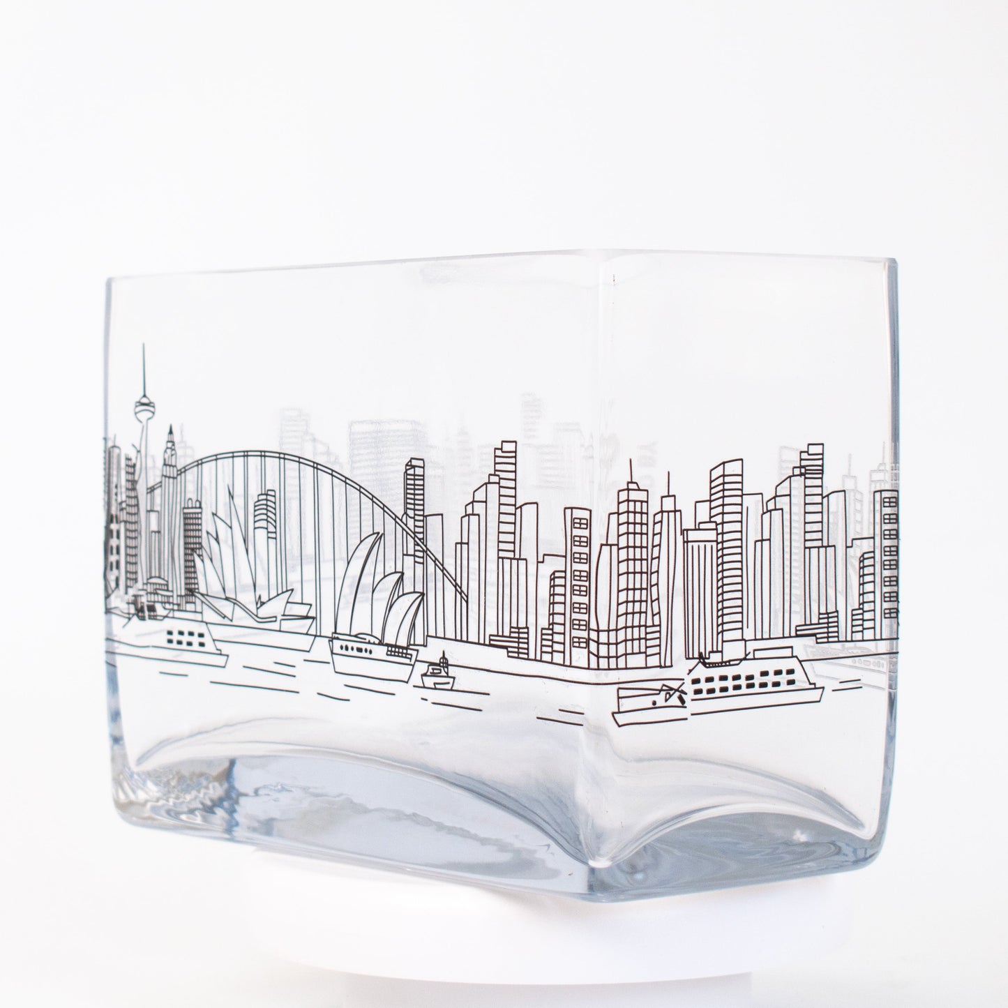 A clear rectangular glass vase featuring a fine-line illustration of the Sydney skyline, including the Opera House, Harbour Bridge, and city buildings.