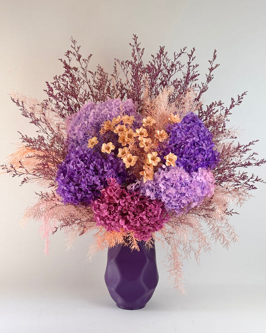Purple vase with a bouquet of purple dried flowers on a white background