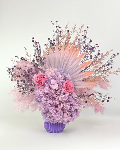Dried Floral arrangement with lilac purple flowers in a purple vase on a white background