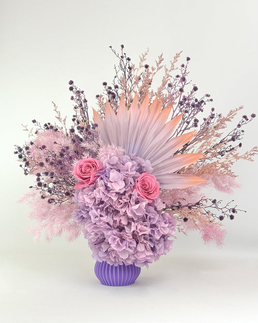 Dried Floral arrangement with lilac purple flowers in a purple vase on a white background