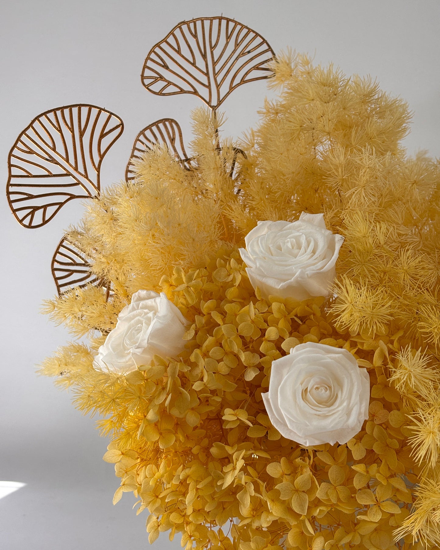 Decorative arrangement of yellow flowers and white roses on a gray background