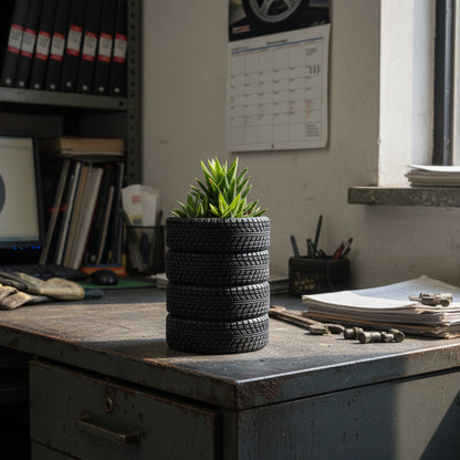 Stack of black tires with a green plant on a white background