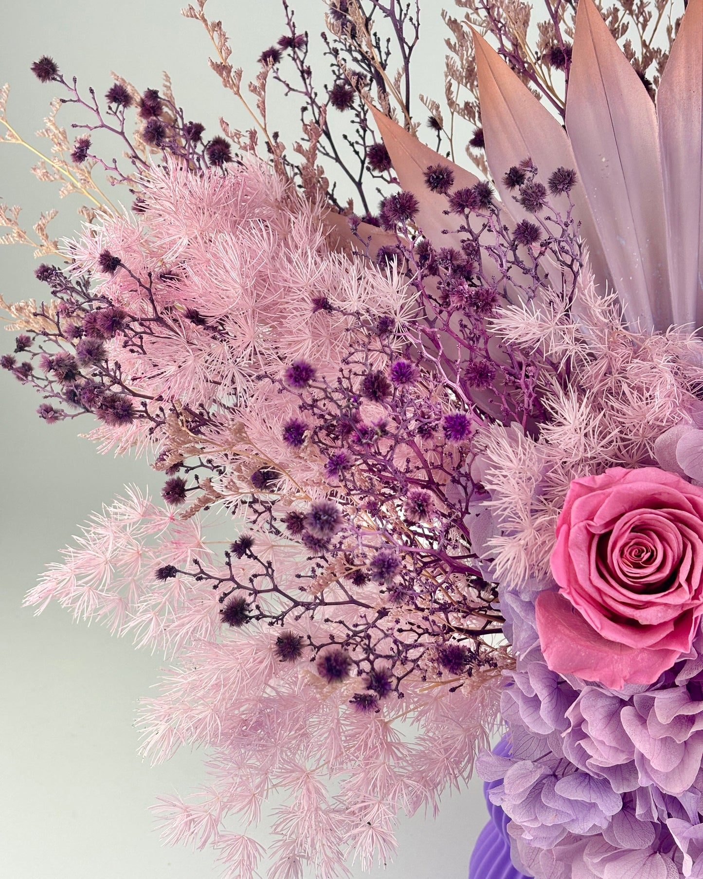 Bouquet of dried flowers in pink and purple with a light gray background