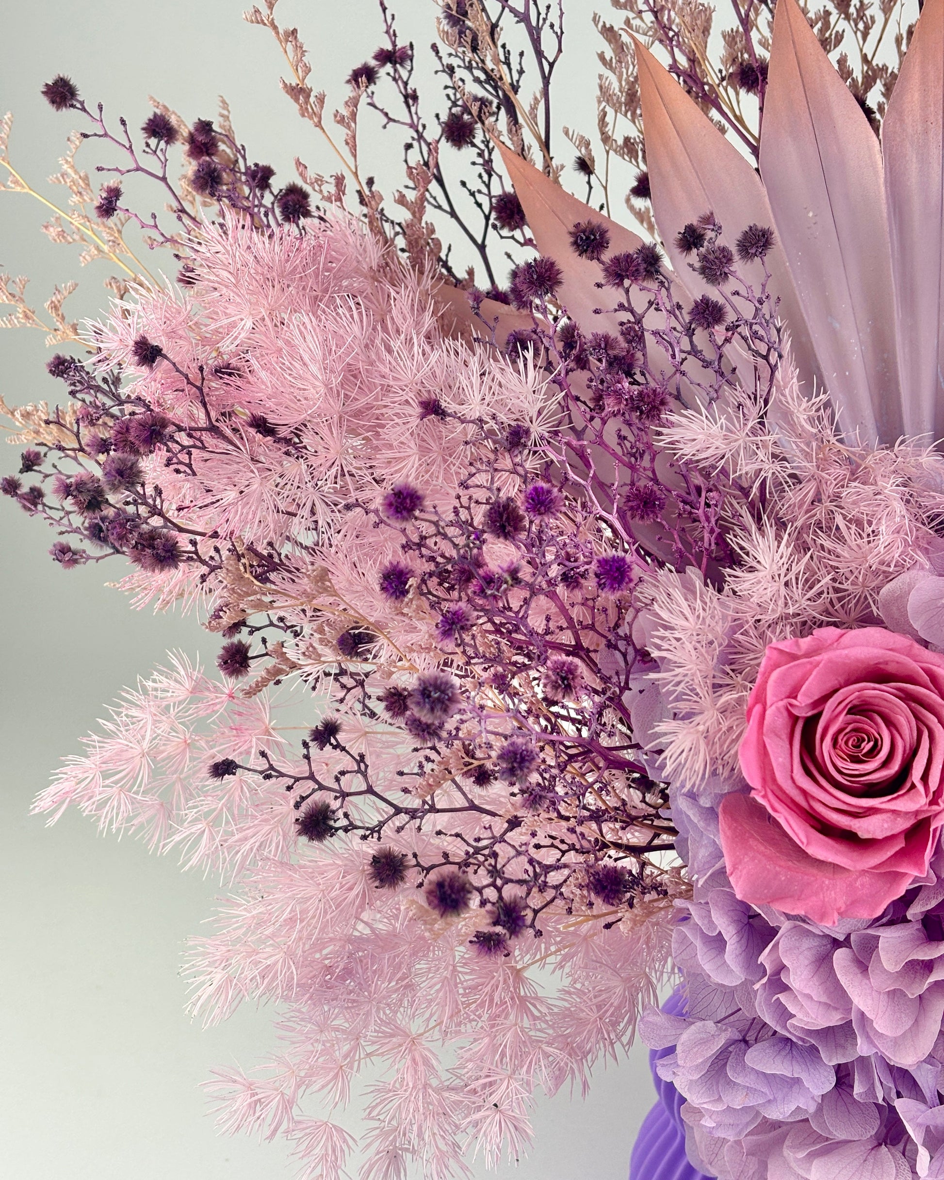 Bouquet of dried flowers in pink and purple with a light gray background