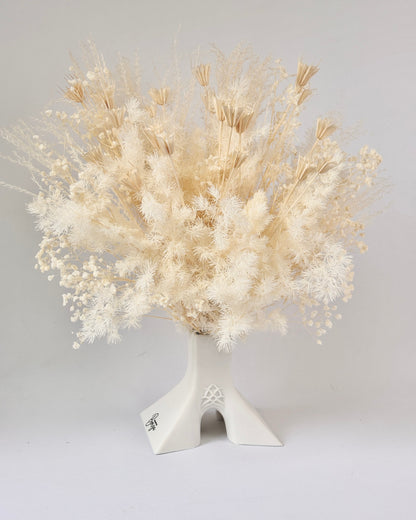 White dried flower arrangement in a decorative vase on a light gray background.