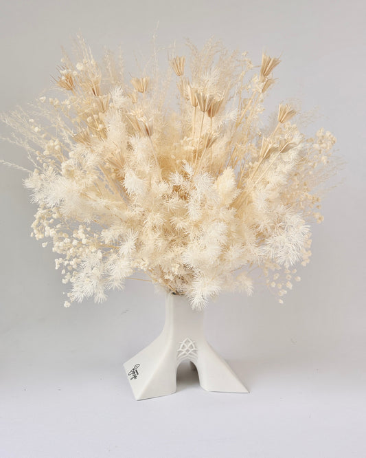 White dried flower arrangement in a decorative vase on a light gray background.
