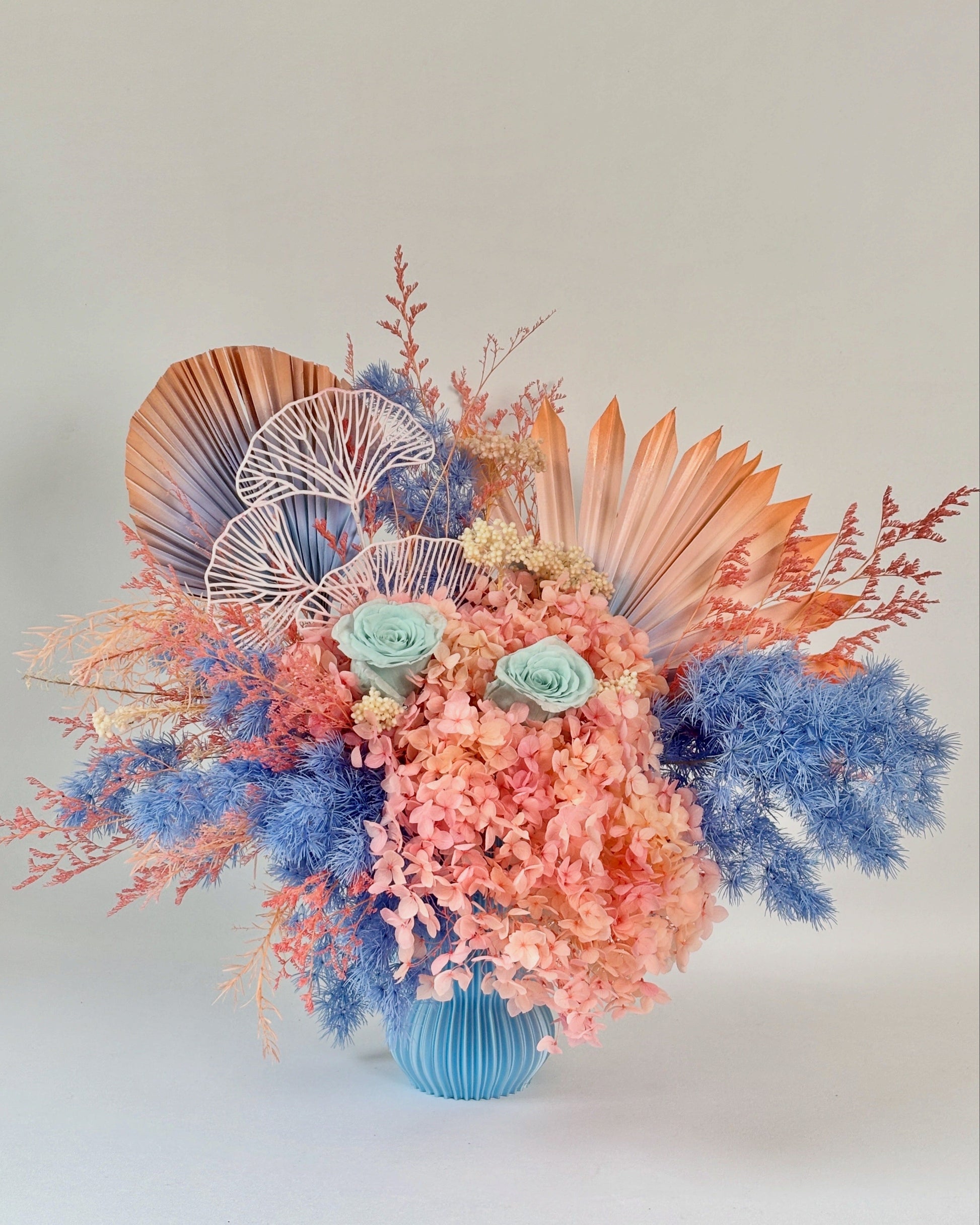 Colourful dried floral arrangement with seashells and coral-like elements on a light background