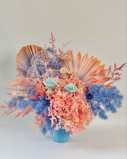 Colourful dried floral arrangement with seashells and coral-like elements on a light background