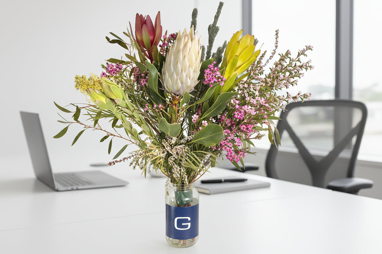 Bouquet of flowers in a clear vase with a blue label on a white office background
