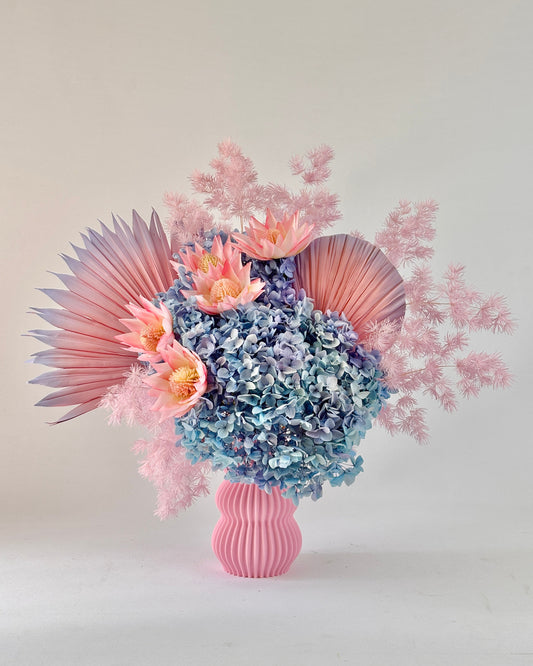 A bouquet of dried flowers in a pink vase 
