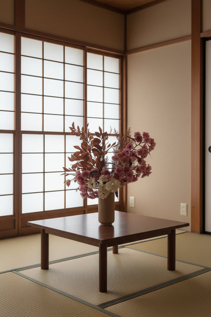 Artificial floral arrangement featuring pink and ivory blossoms with rust-colored foliage, elegantly styled in a tall ribbed nude vase.