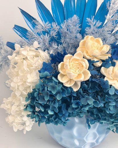 Bouquet of blue and white dried flowers in vase on a light background