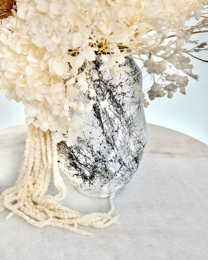 Decorative vase with white flowers and beads on a light background