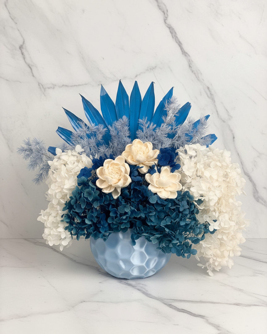 Bouquet of blue and white flowers in a clear vase on a marble surface