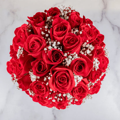 Fresh red roses arranged in a white round hat box with baby’s breath
