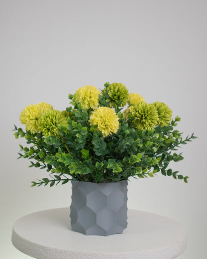 Artificial arrangement with lime-yellow blooms and lush greenery in a modern grey geometric vase