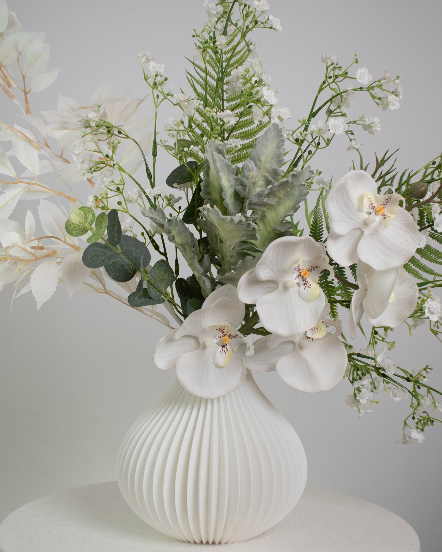 Luxury artificial orchid arrangement with white blooms and greenery for home or office décor.