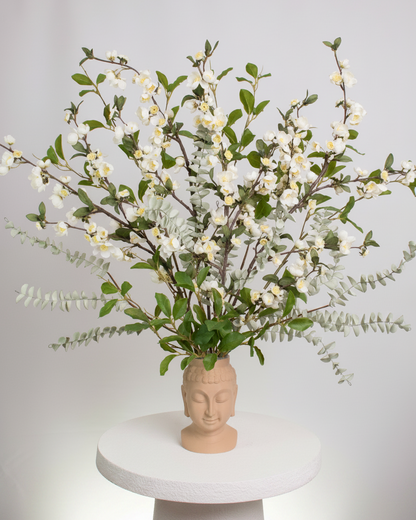 Vase with floral arrangement on a white pedestal against a light gray background