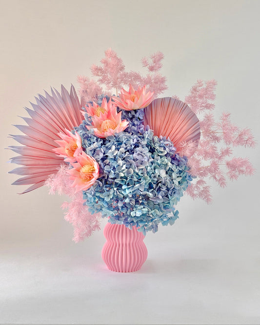 Floral arrangement with pastel-coloured flowers in a pink vase on a light background