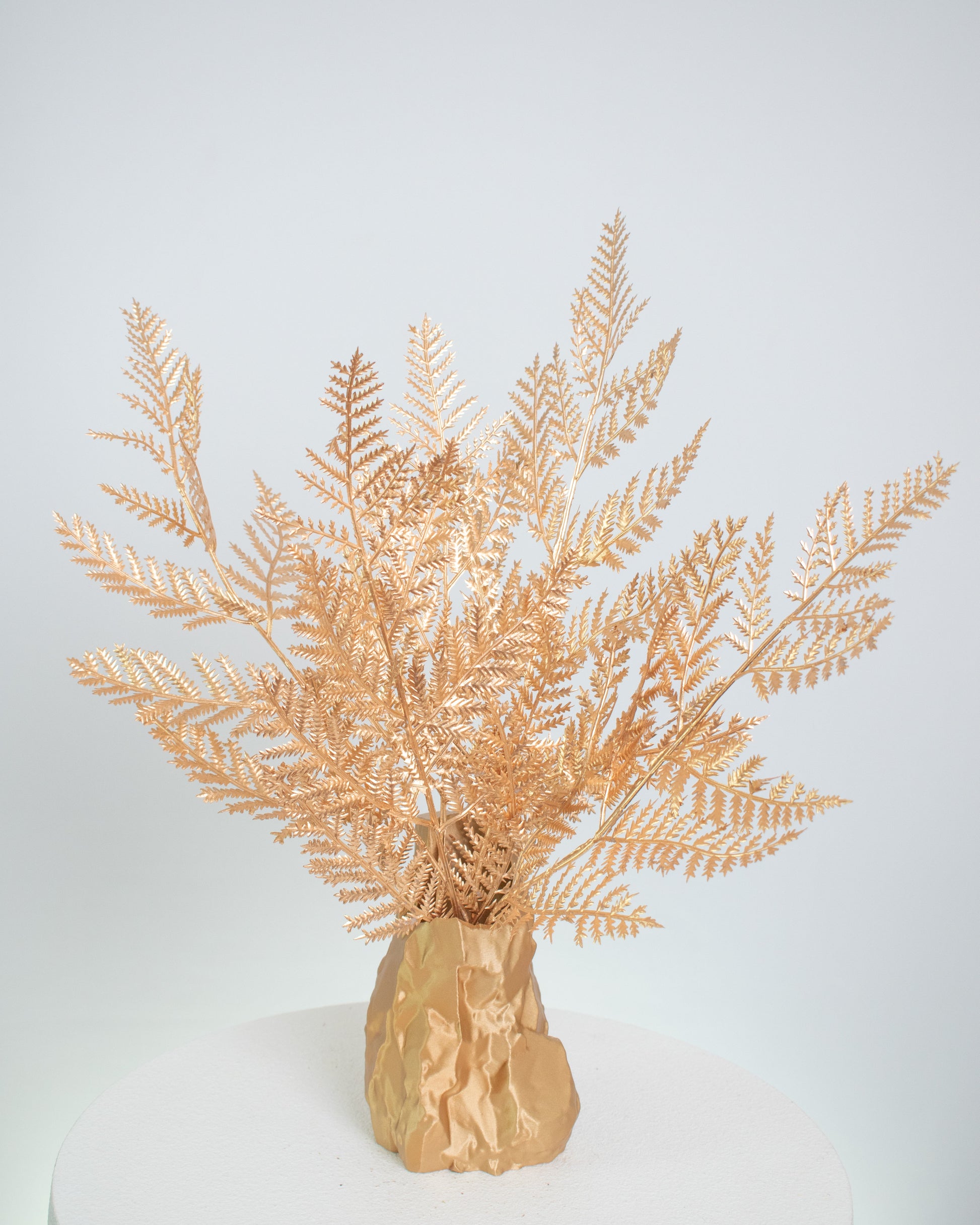 Artificial gold fern arrangement in a sculptural gold vase, styled on a marble table — a modern, luxurious decorative piece ideal for elegant and minimalist interiors.