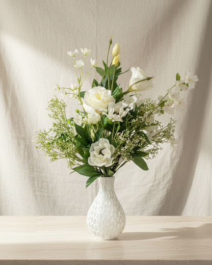 White vase with a bouquet of flowers on a wooden surface against a beige curtain background