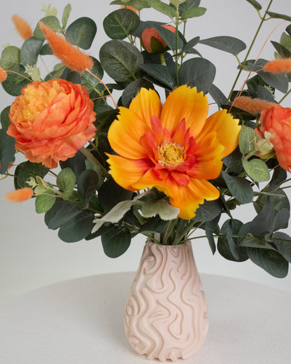 Floral arrangment with the warm orange tones and lush greenery, giving a calm yet lively feeling, perfect for brightening modern or neutral spaces.