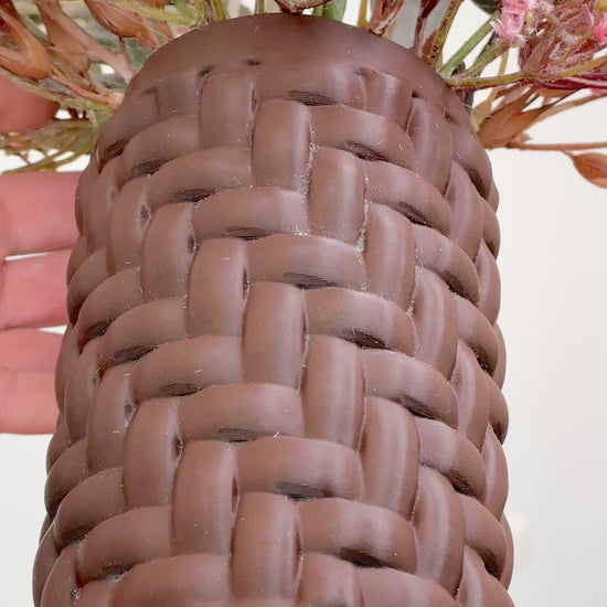 Artificial floral arrangement with blush pink flowers and rustic brown foliage in a woven brown vase, styled on a marble table — a warm, elegant decorative piece perfect for neutral or earthy interiors.