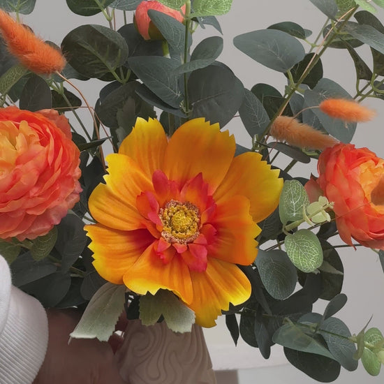 Floral decor with the warm orange tones and lush greenery, giving a calm yet lively feeling, perfect for brightening modern or neutral spaces.