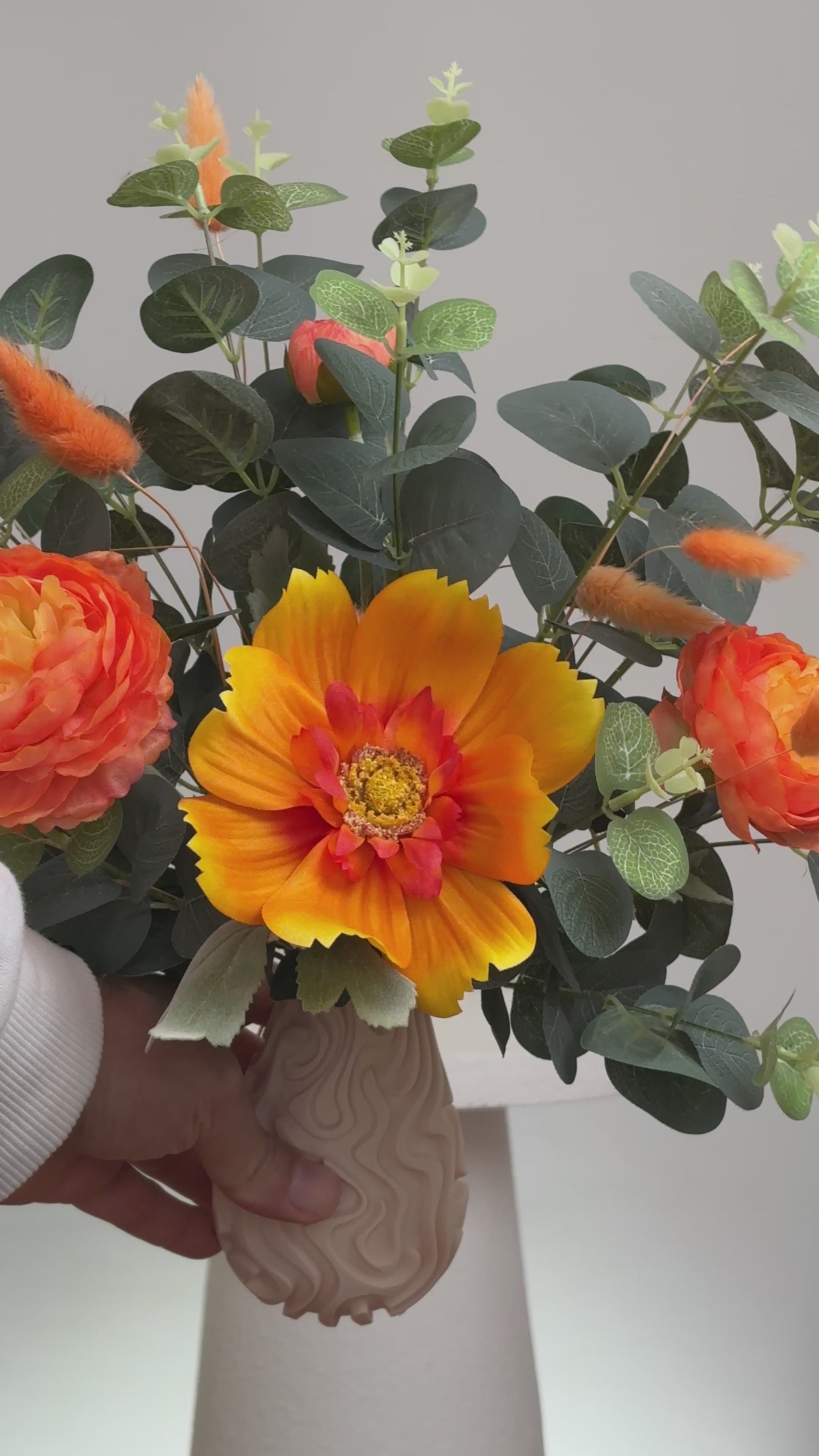 Floral decor with the warm orange tones and lush greenery, giving a calm yet lively feeling, perfect for brightening modern or neutral spaces.