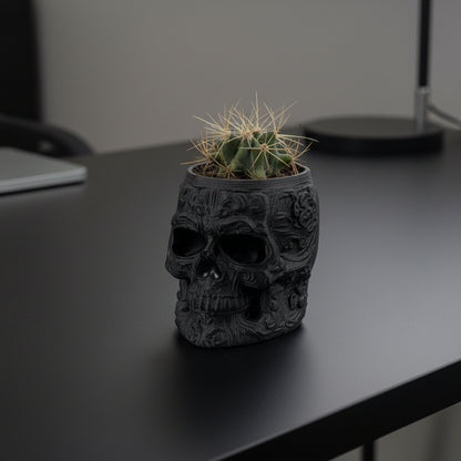 Black skull-shaped planter with a cactus on a gray background.