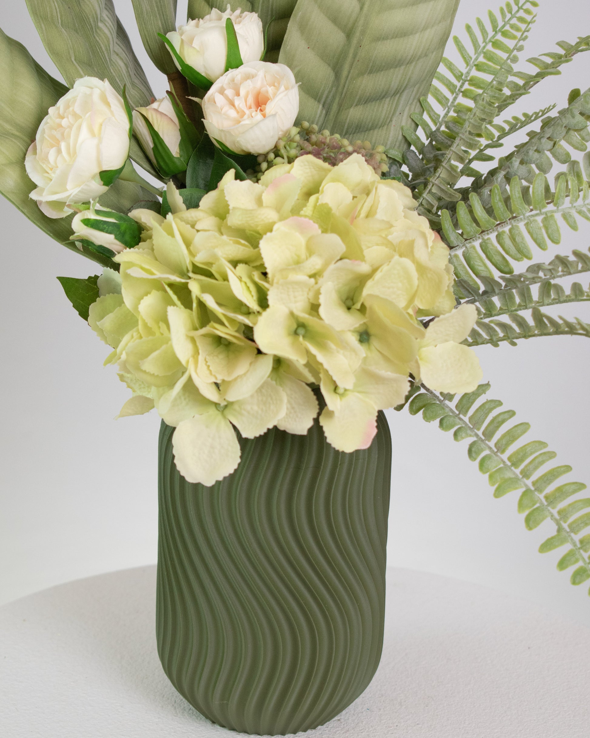Green vase with wavy texture holding a bouquet of flowers Realistic lifelike artificial flowers and foliage